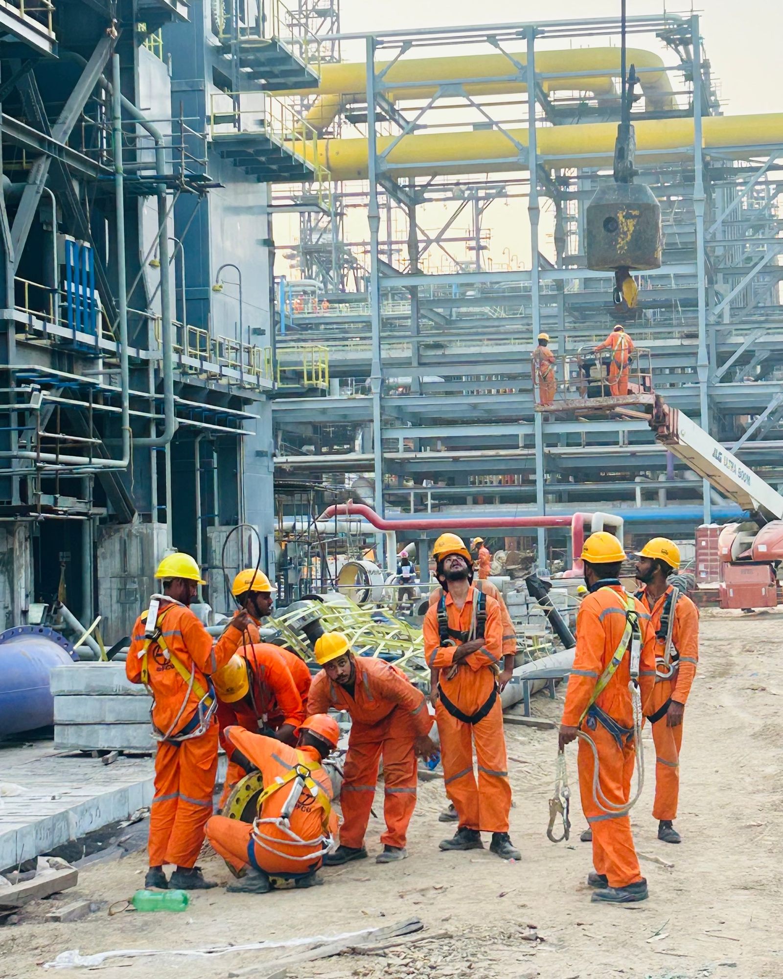 An industrial maintenance crew in protective clothing and safety harnesses at a plant